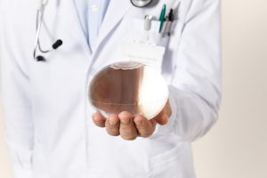 Allurion_Promotional_Images-24-300x200 - Instituto de Obesidad Doctor in a white coat holding a glass round-bottom flask with brown liquid, stethoscope visible.